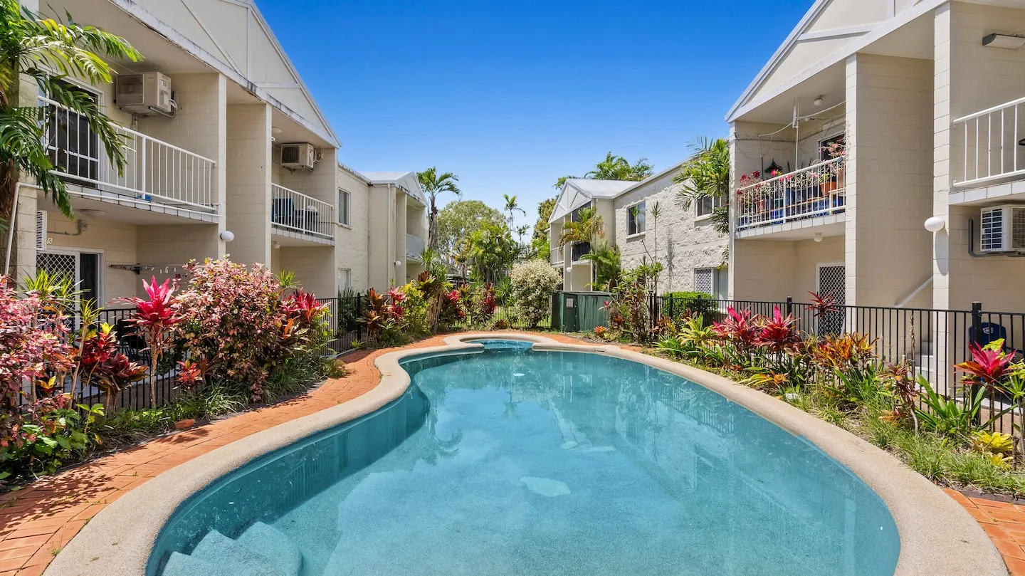 Curved swimming pool surrounded by palms and flowers